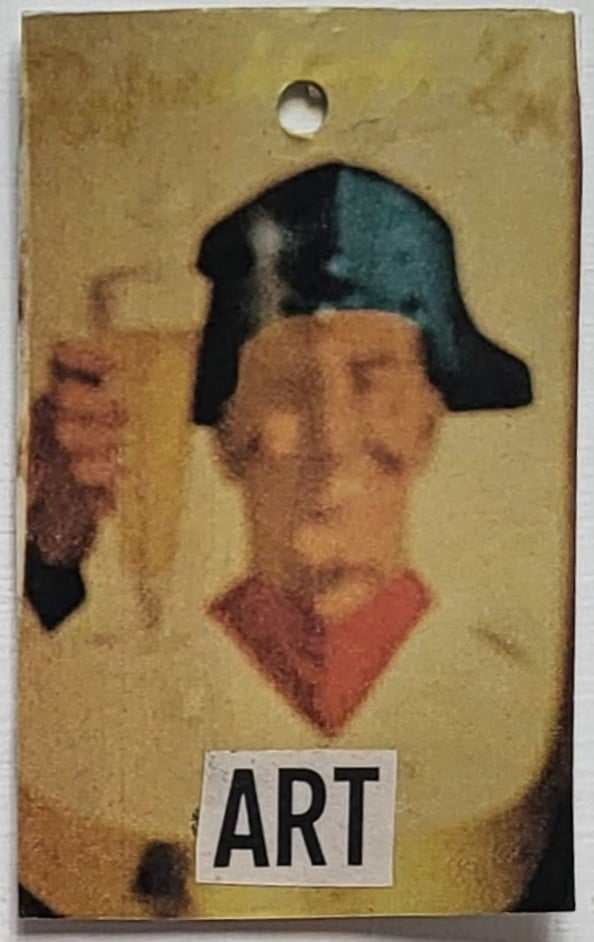 An out of focus man in an admirals hat holds up a pint of beer. Below him is cut out text saying the word ART in capital letters